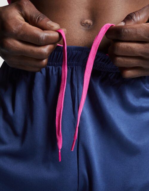 Person binder lyserødt snørebånd på blå shorts.