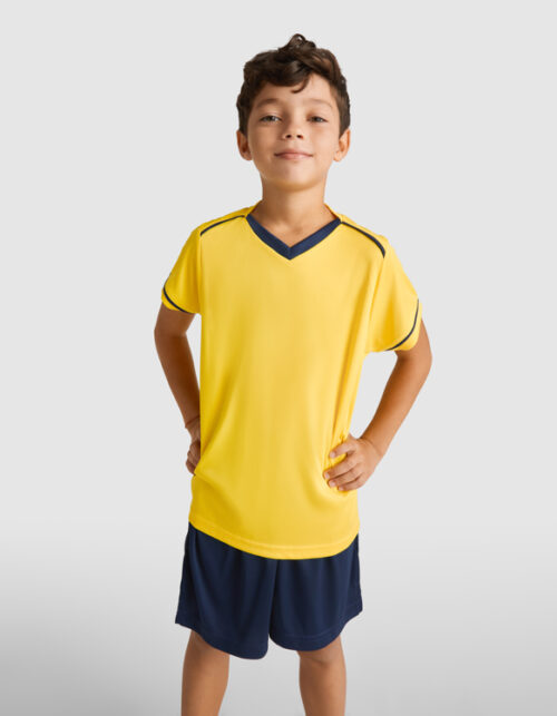 Dreng i gult sportstøj med hænderne på hofterne.