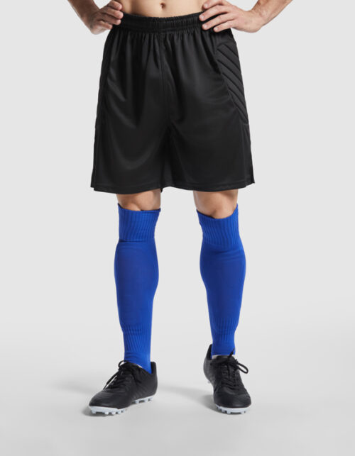 Fodboldspiller i sorte shorts og blå sokker