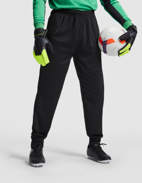Goalkeeper i bukser med handsker og fodbold.