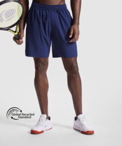 Mand i blå shorts holder en tennis-ketcher.