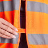 Hånd lukker orange refleksvest med velcro