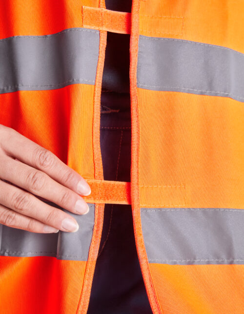 Hånd lukker orange refleksvest med velcro