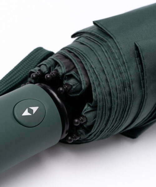 Sammenfoldet mørkegrøn paraply med håndtag